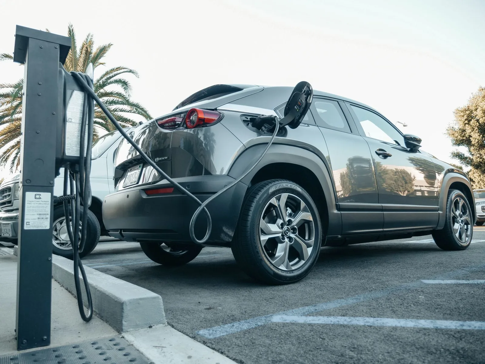 An electric car plugged into a charging unit in a parking area
